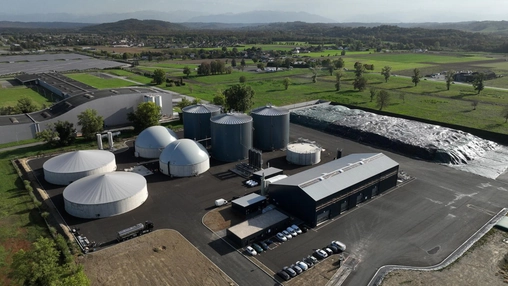 Aerial view of a biogas production plant with digesters and storage tanks surrounded by farmland