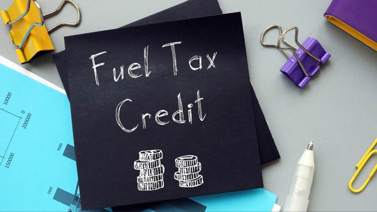 Fuel tax credit note surrounded by office supplies and charts on a desk.
