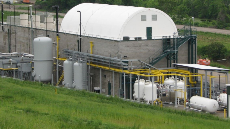 Landfill gas processing facility with tanks and piping on a grass-covered site